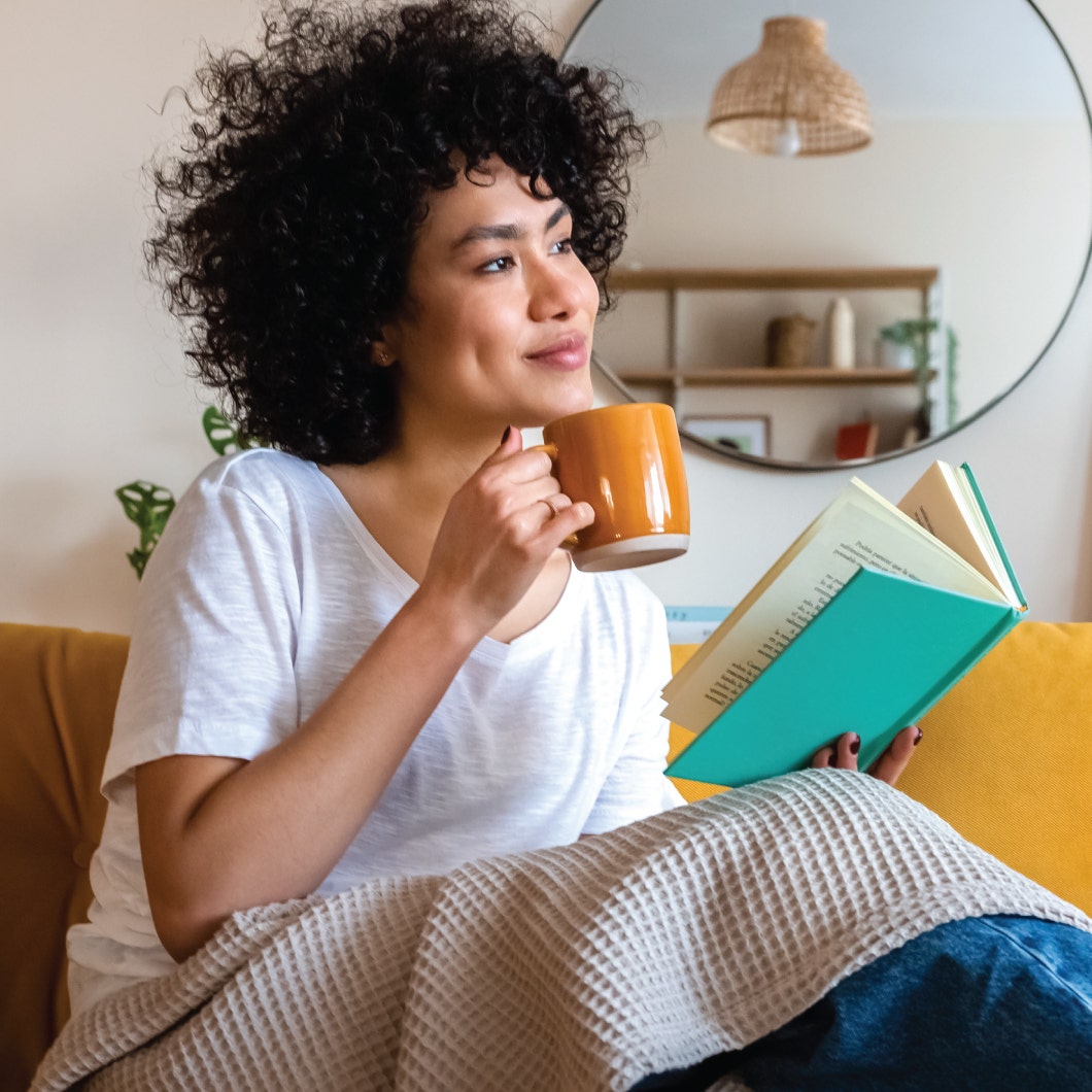 Woman drinking a cup of coffee and reading a book