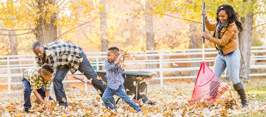 family playing in fall leaves