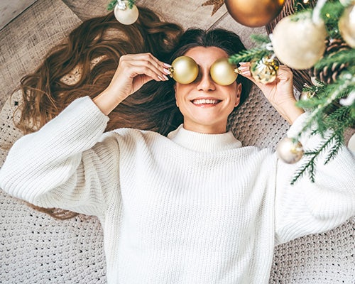 girl holding ornaments under a christmas tree